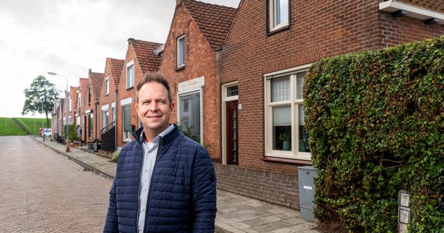 Theo van der Sluijs staat in een straat met bakstenen rijtjeshuizen